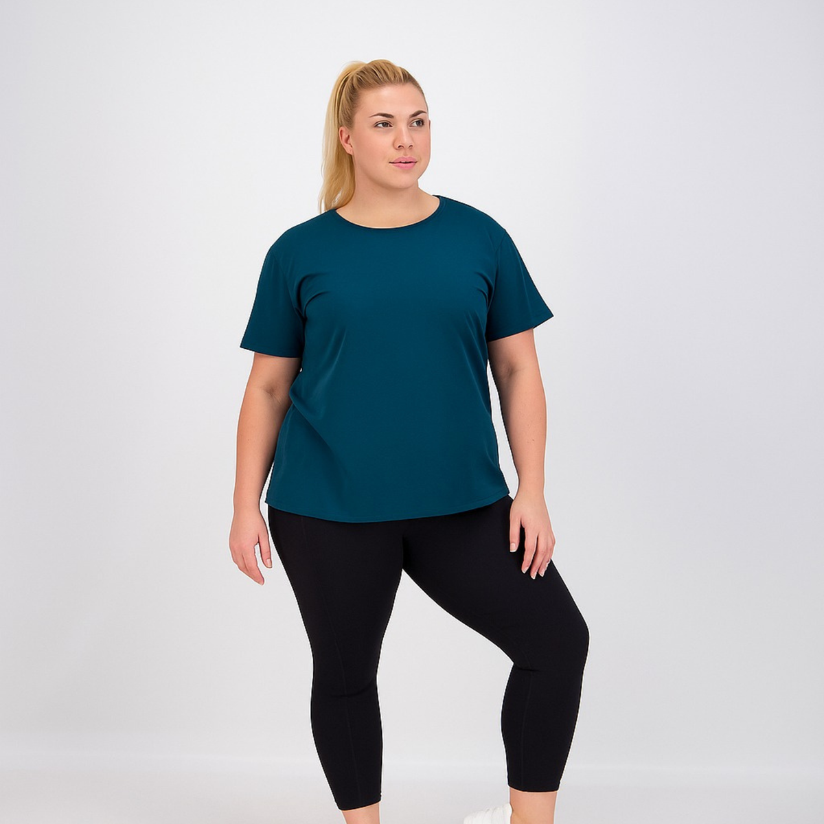 Woman wearing a teal shirt and black leggings on a white background